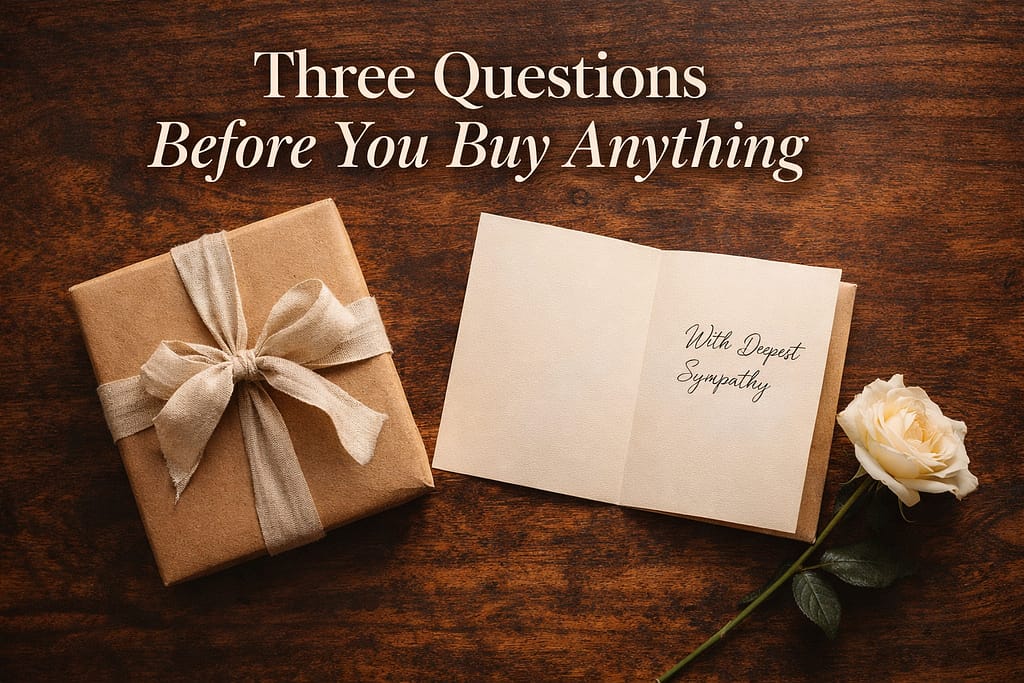 Overhead flat lay of a wrapped gift box, sympathy card, and white rose on a dark walnut table