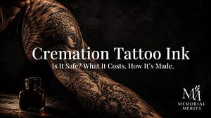 Elaborate black-and-grey memorial tattoo on a man's forearm lit in dramatic low light beside a glass bottle of cremation tattoo ink